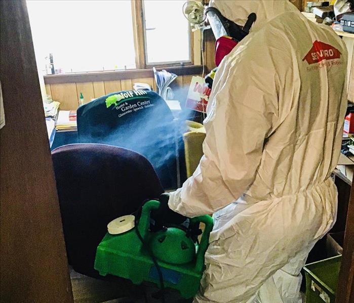 Man in biohazard suit spraying an office 